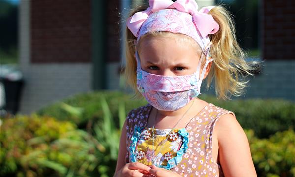 girl smiles while wearing mask